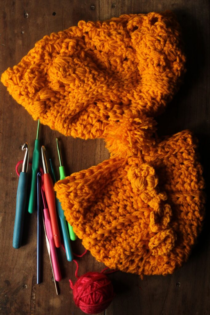 Orange crochet hat with crochet hooks