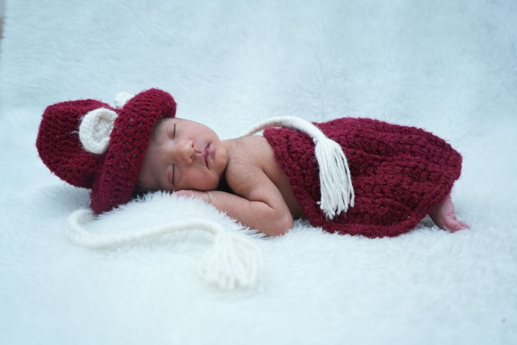 Adorable baby in knitted red outfit sleeping peacefully