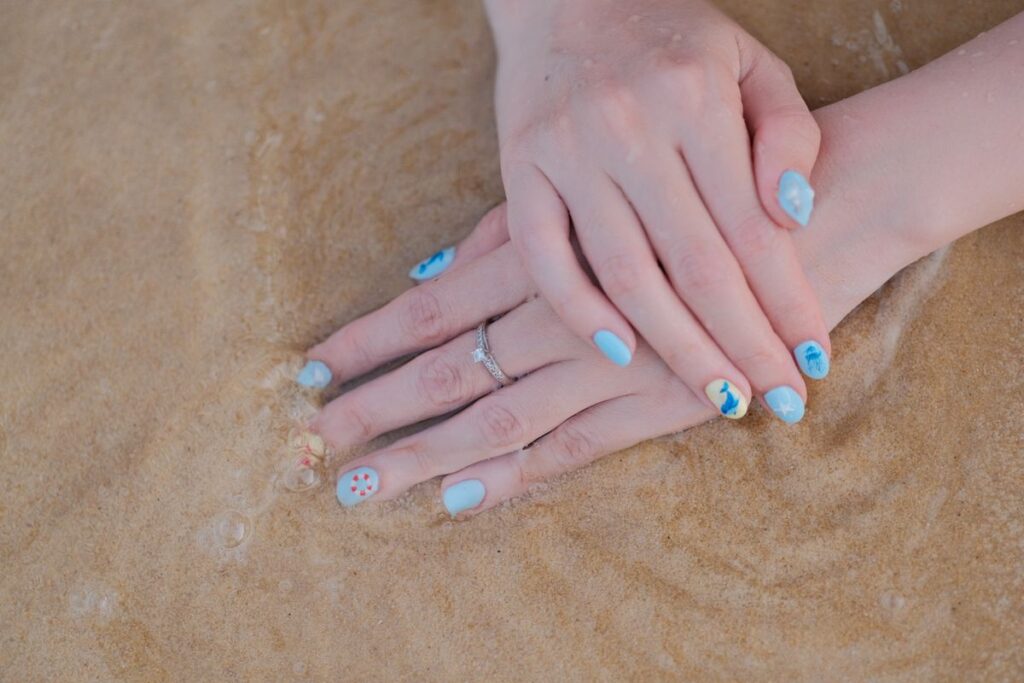 Close up of hands with beach nail art on sand