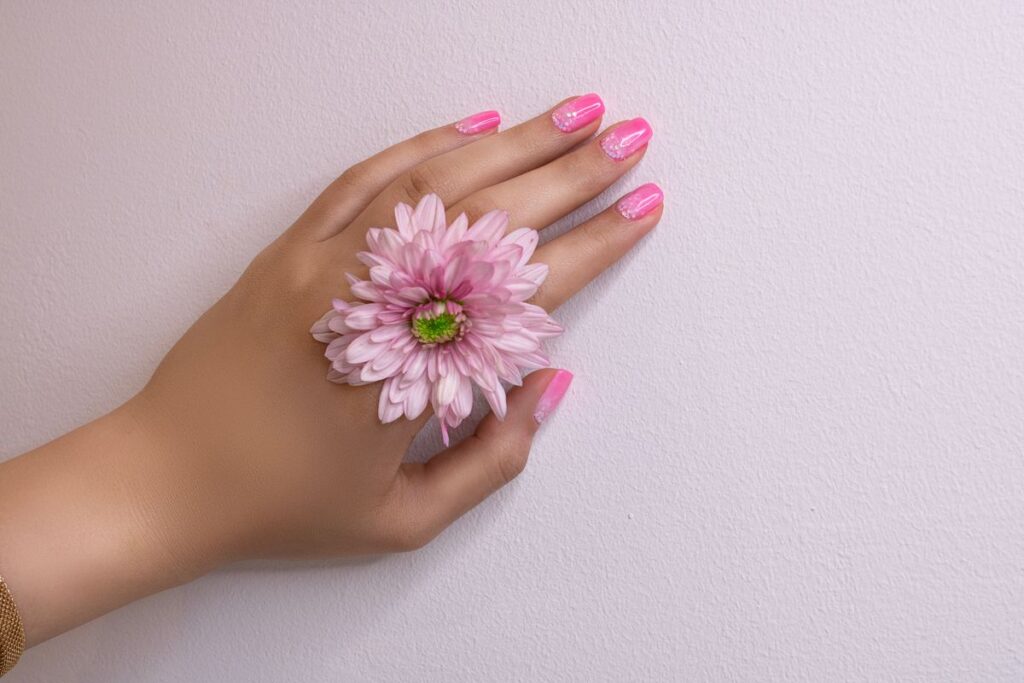 Pink flower on hand with polished nails