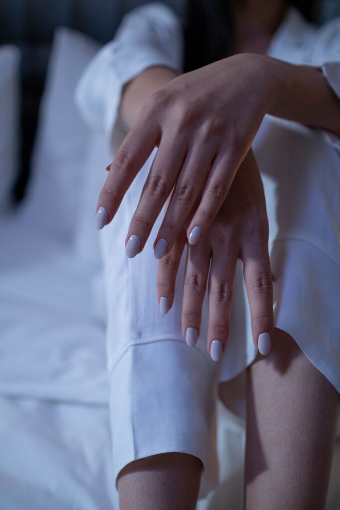 Selective focus shot of a person's hands with white nail polish