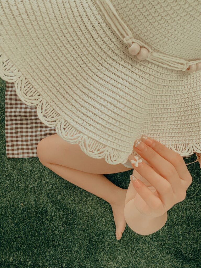 Sunhat worn by a woman with decorated acrylic nails