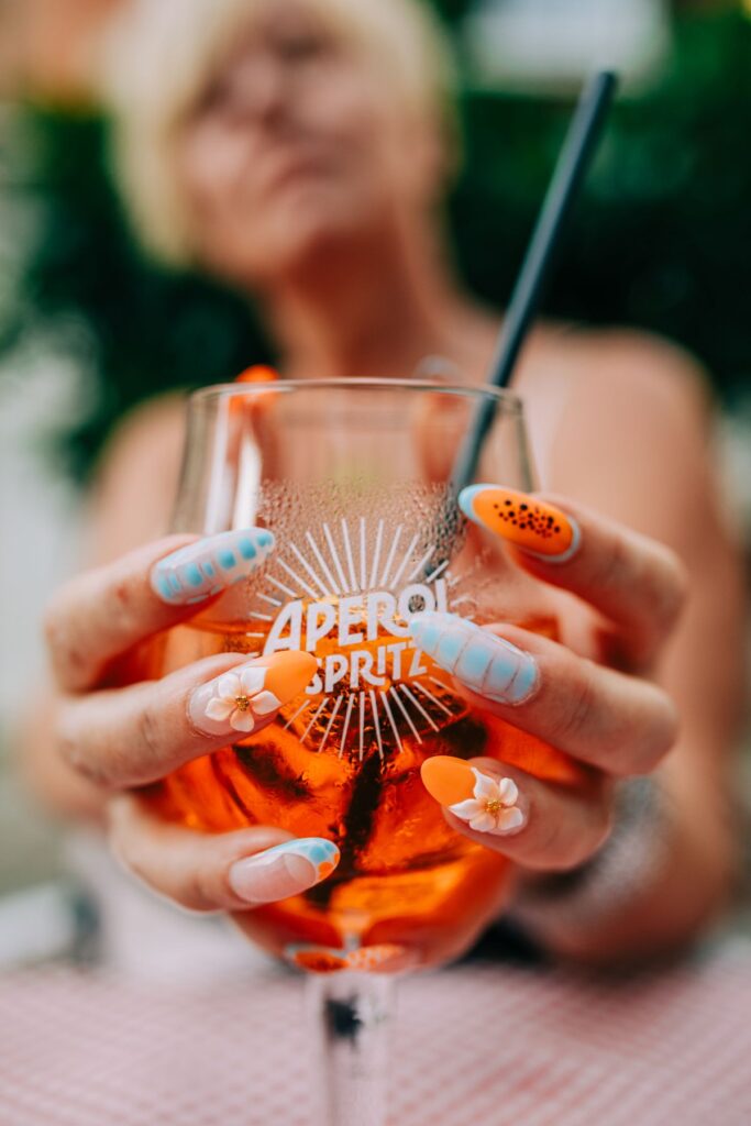 Vibrant aperol spritz with artistic nails